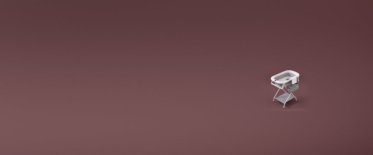 Baignoire bébé pliable Treelys sur son support, serviette sur le rebord, fond mauve