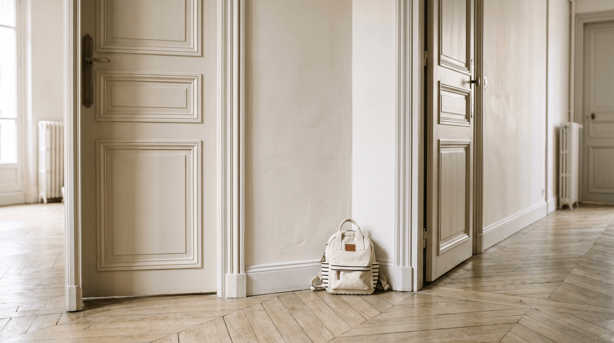 Couloir avec deux encadrements de porte et un petit sac d'enfant posé au sol — garde alternée bébé — Treelys®