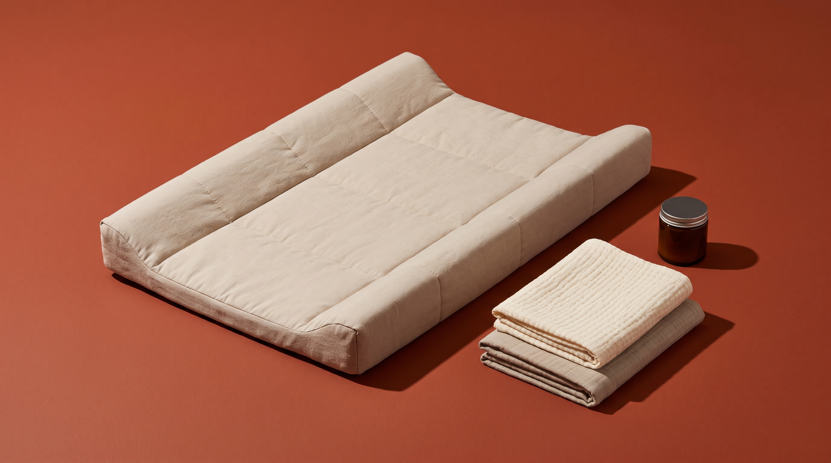Matelas à langer aux rebords relevés posé sur fond uni, langes en coton pliés à côté — Treelys®